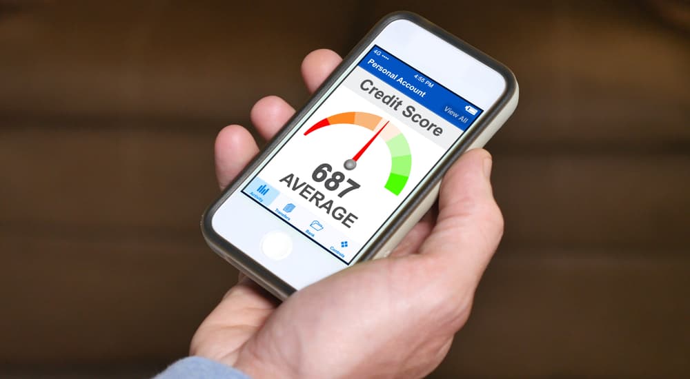 A smartphone is showing a credit score app with average credit.