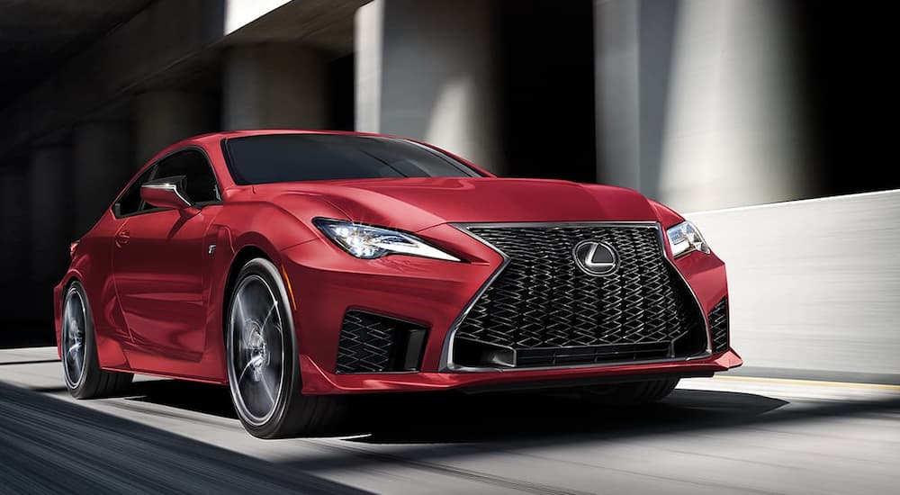 A red 2020 Lexus RCF, with its new release in current auto news, is driving in front of buildings.