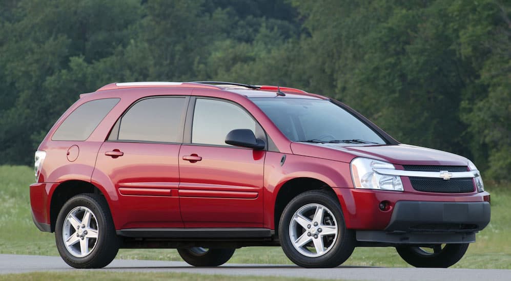 A red 2009 Chevy Equinox is parked on a road with trees in the background. 