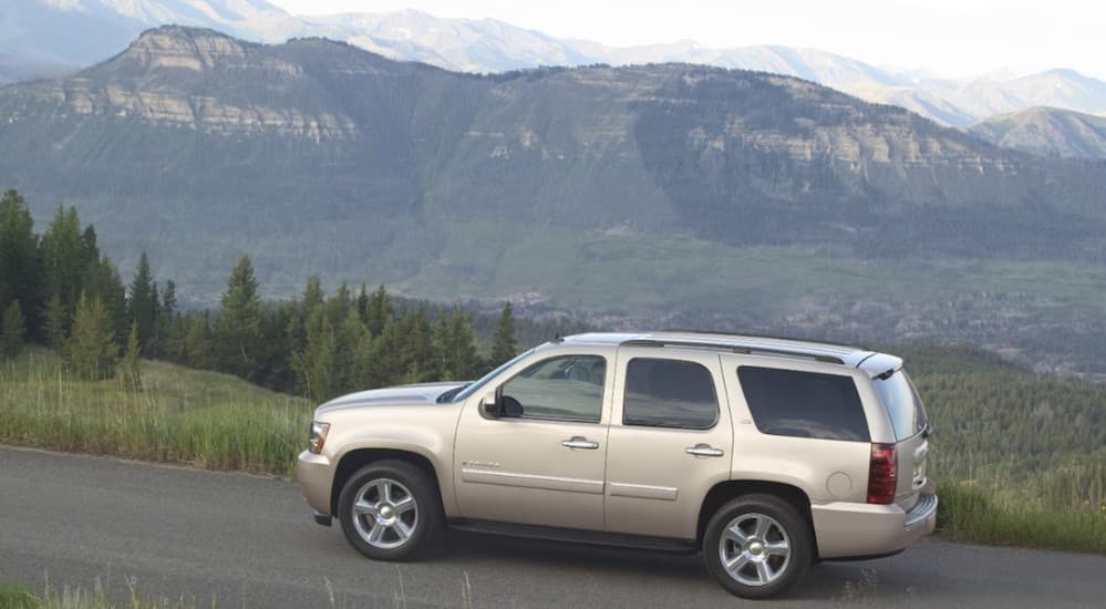 A silver 2010 Chevy Tahoe parked on a road with mountains in the background. 