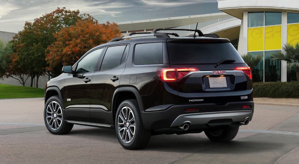 A 2019 GMC Acadia is shown in front of a building facing away.