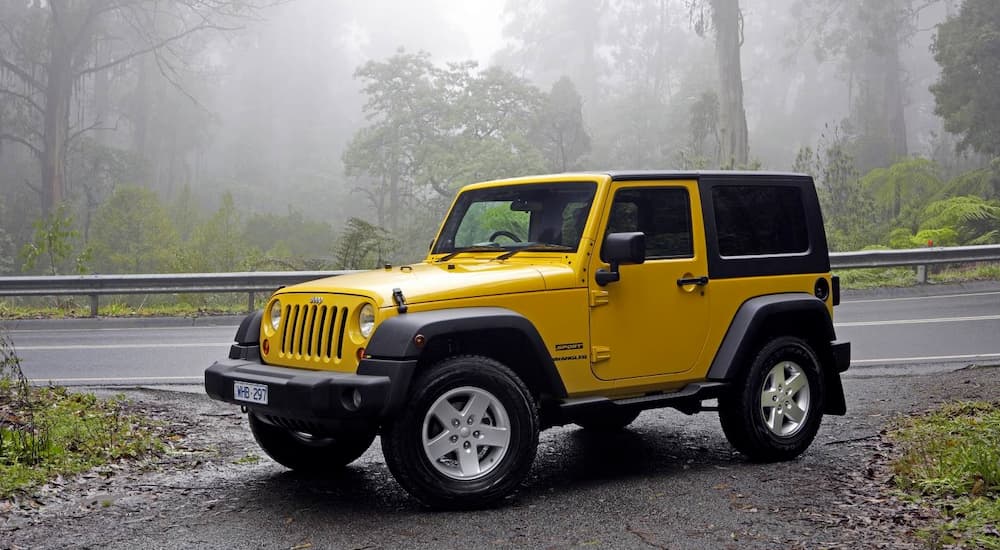 A yellow 2008 Jeep Wrangler, popular among used cars, is parked in the fog.