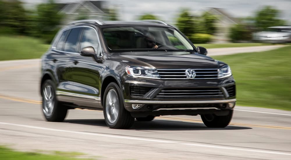 A black 2015 Volkswagen Touareg is driving in a neighborhood.