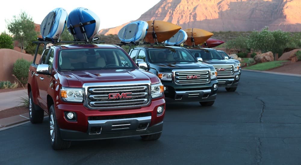 Four 2016 GMC Canyons are parked with kayaks and paddle boards on the bed racks.