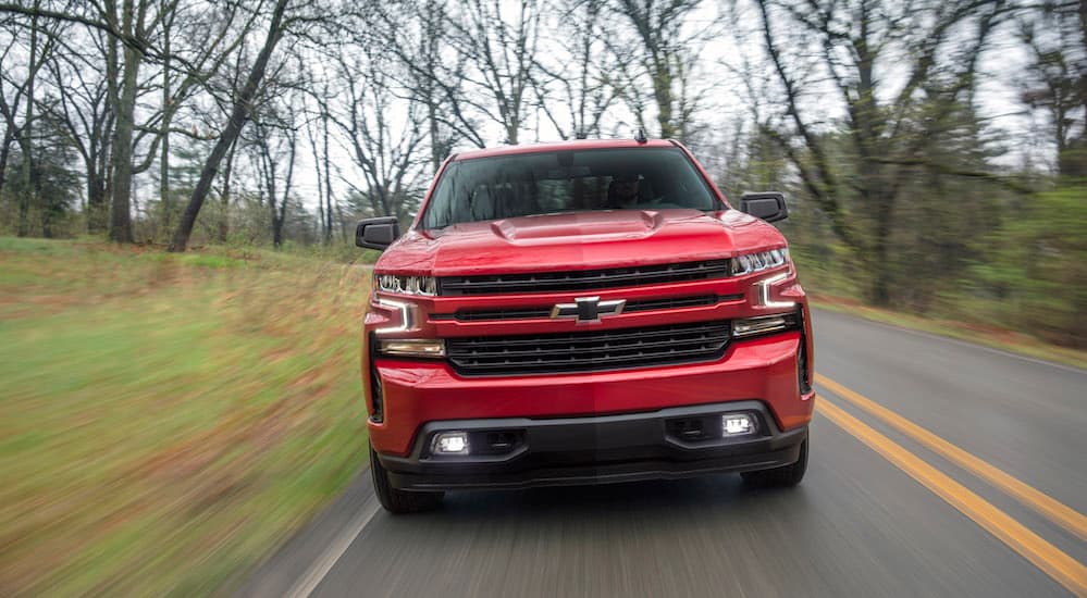A red 2019 Chevy Silverado is shown driving down a road after leaving a Chevy dealership. 