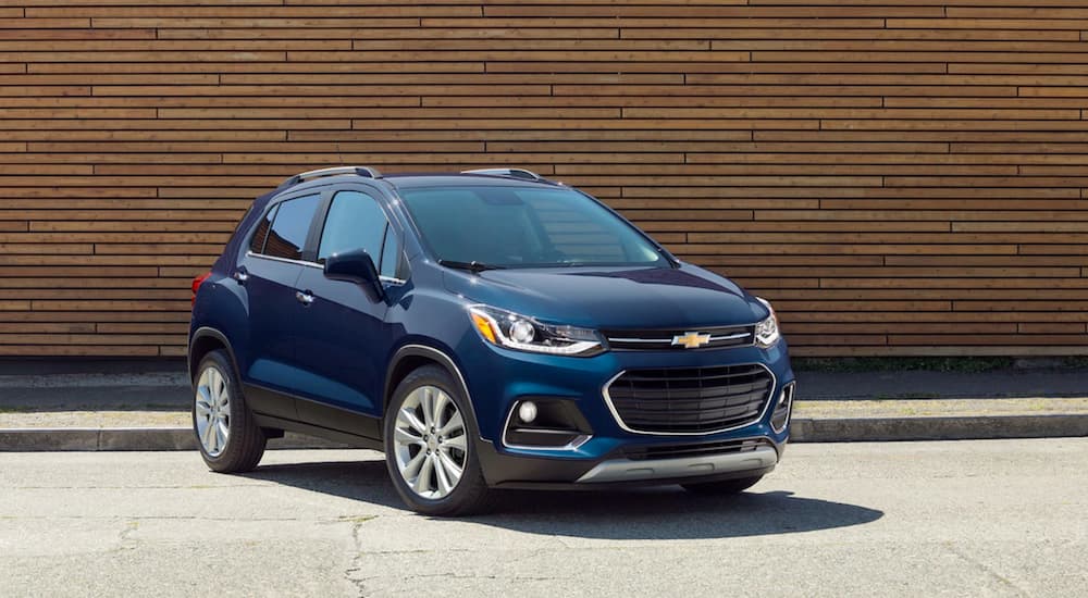 A blue 2019 Chevy Trax is parked in front of a wood wall.