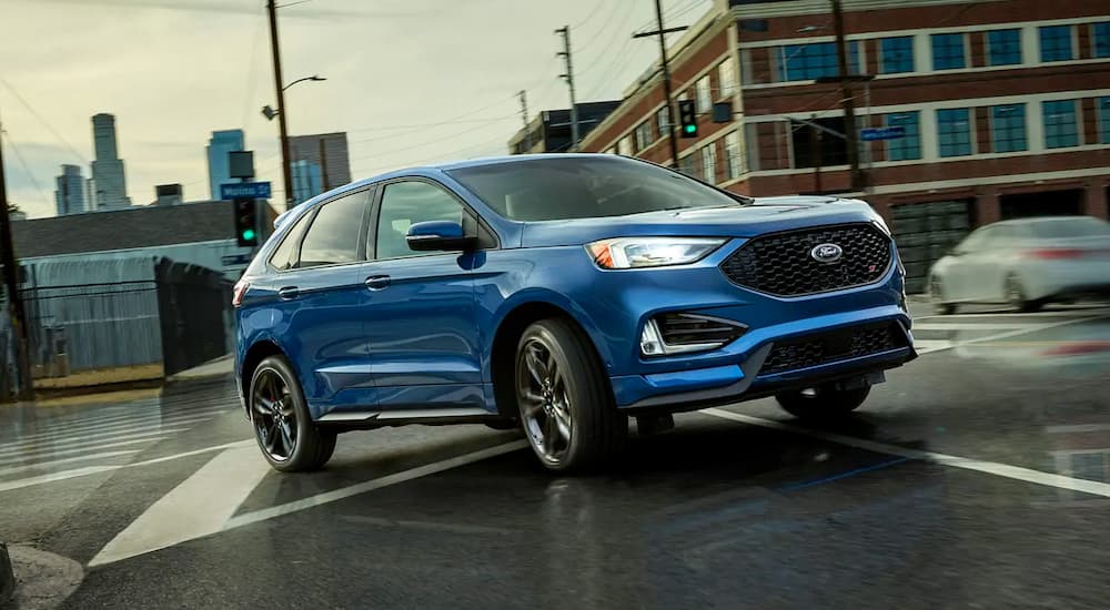 A blue 2019 Ford Edge ST, which wins when comparing the 2019 Ford Edge vs 2019 Kia Sorento, is taking a corner in an intersection.