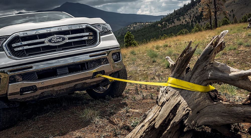 A white 2019 Ford Ranger is pulling a stump with a tow strap attached to the front tow hook.