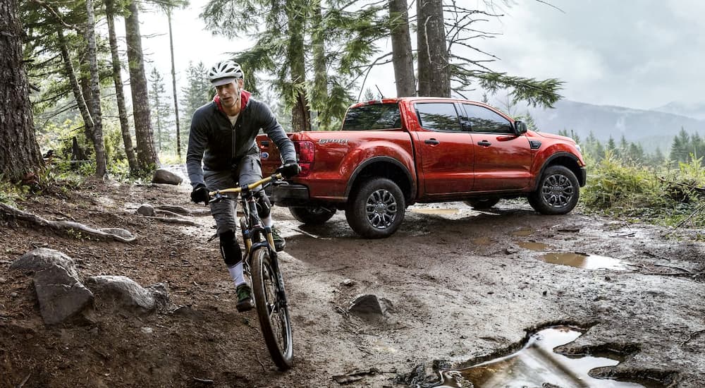 A biker is riding away from his red 2019 Ford Ranger is parked off road.