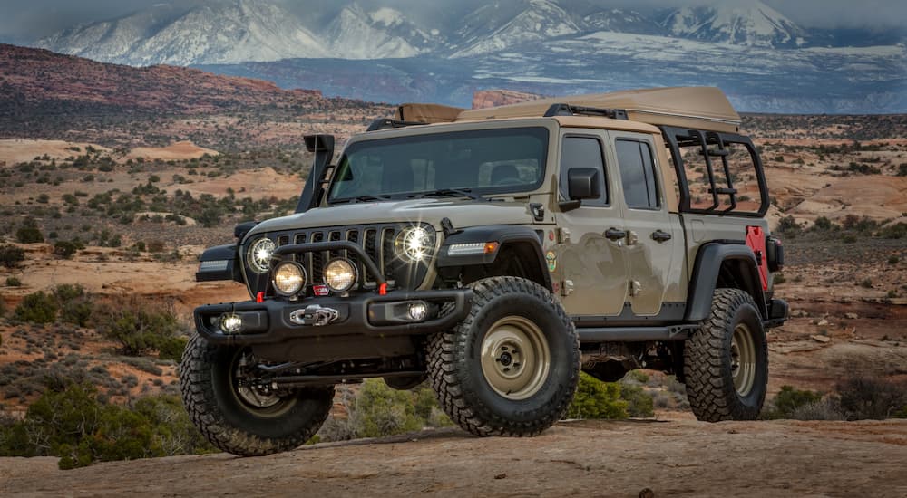 The tan 2019 Jeep Gladiator Wayout build is shown in a desert with mountains behind it.