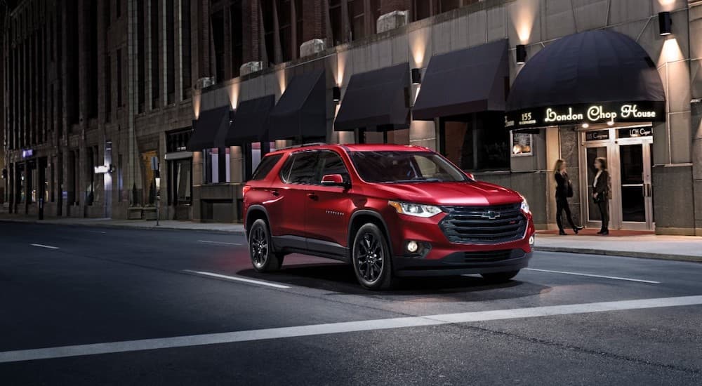 A red 2019 Chevy Traverse is at an intersection at night.