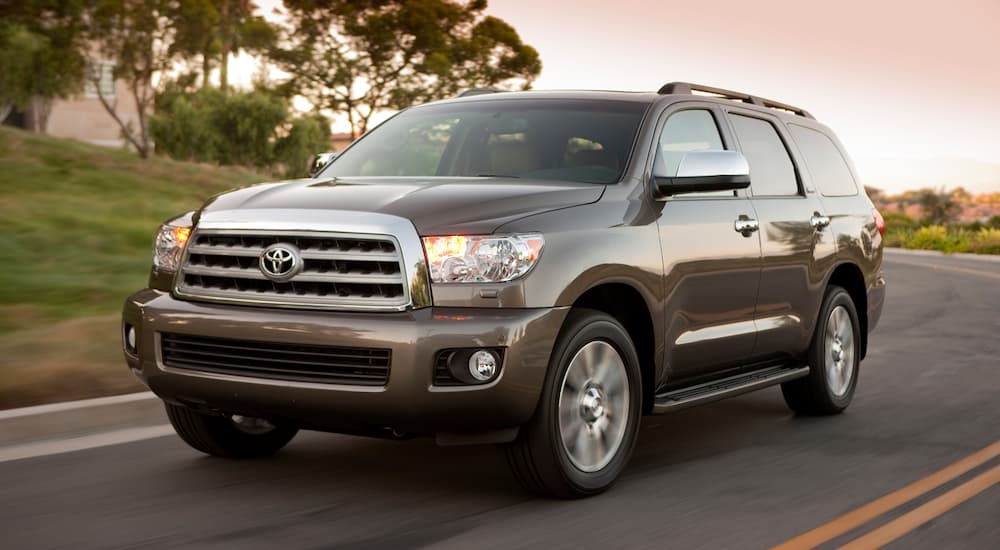 A tan 2012 Toyota Sequoia is driving at sunset.