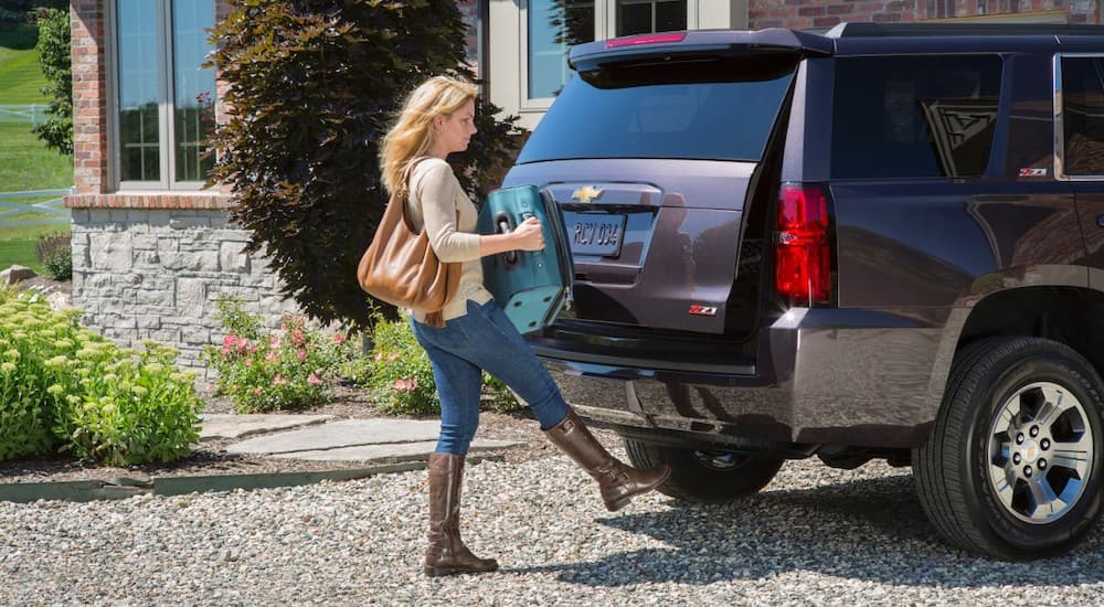 A woman is loading a suitcase into the back of her 2016 Chevrolet Tahoe Z71. 