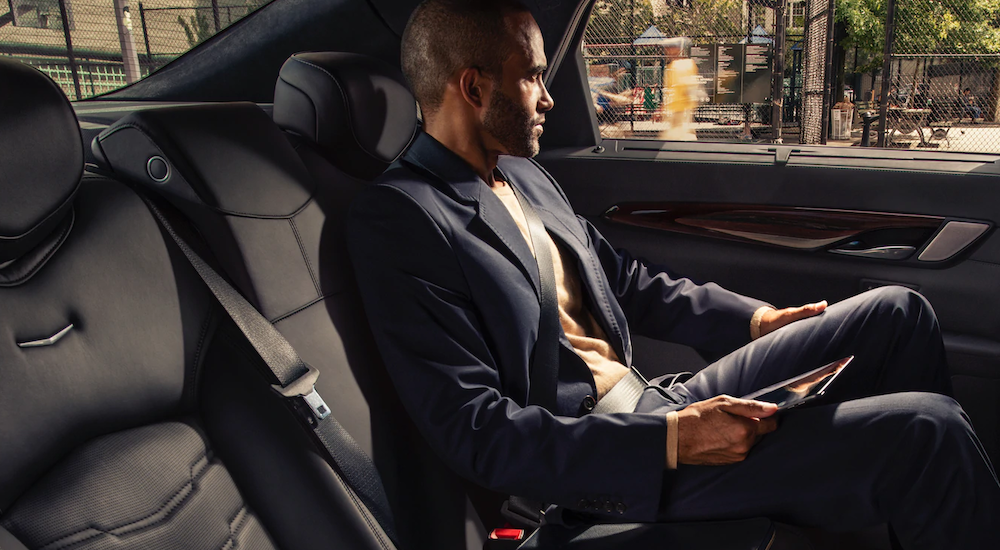 A man is in the backseat of a 2019 Cadillac CT6 with black interior.