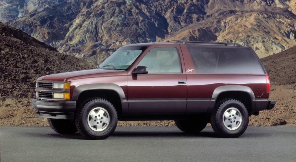 A maroon 1995 Chevy Tahoe Sport is parked in front of mountains.