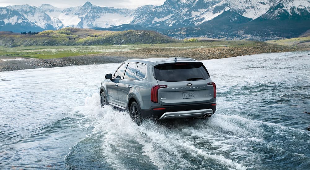 A blue 2020 Kia Telluride is crossing a river.