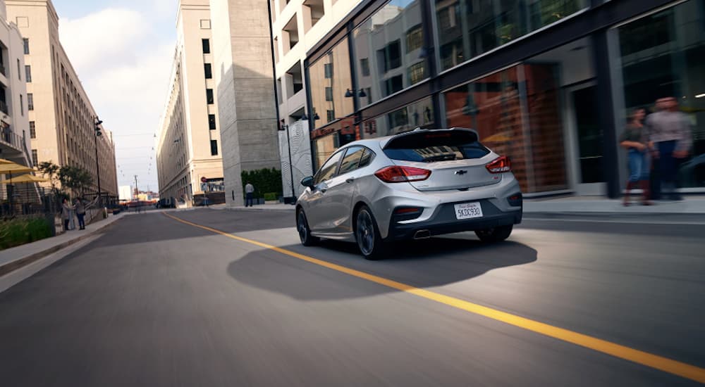 A silver 2019 Chevy Cruze hatchback is driving downtown.