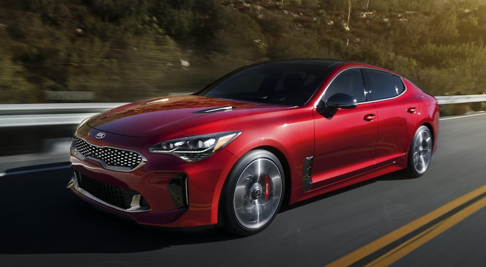 A red 2019 Kia Stinger is driving on a highway.