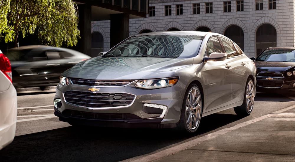 A silver 2018 Chevy Malibu is driving downtown near Dallas.