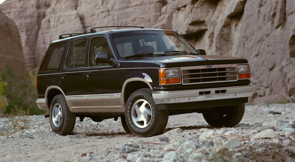 A black 1991 Ford Explorer, an older Ford SUV for sale, is parked in front of a rocky cliff.