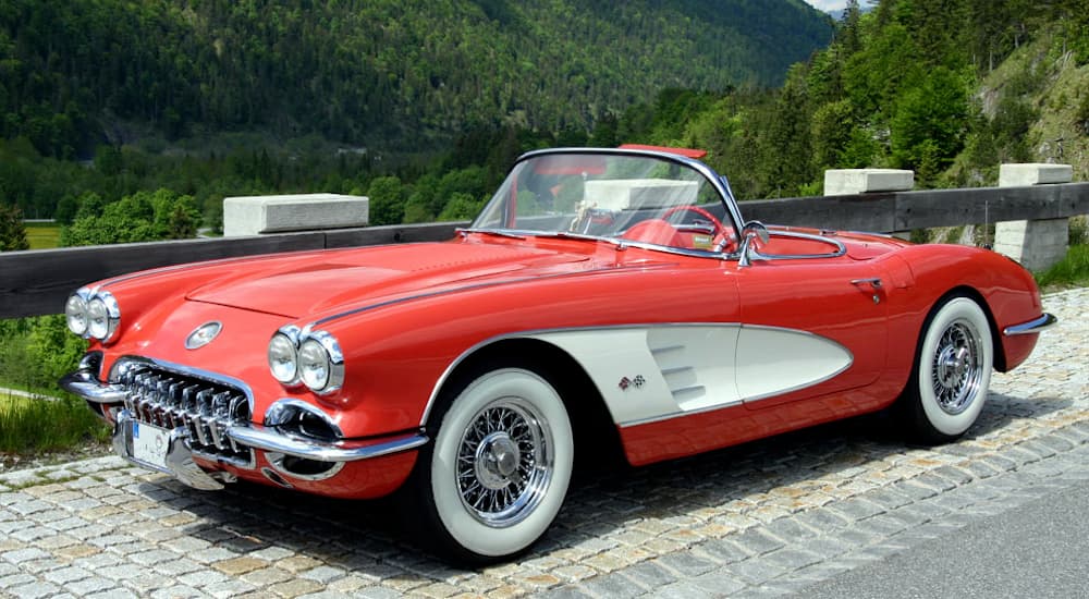 A red 1958 Chevy Corvette is parked with views of green hills.