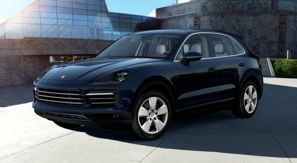 A blue 2019 Porsche Cayenne, a popular manufacturer among Ohio celebrities dream cars, is parked in a modern house's driveway.