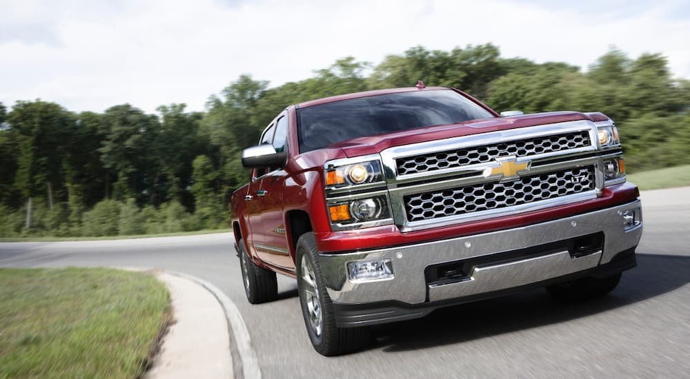 A red 2015 Chevy Silverado 1500 is driving around a corner.