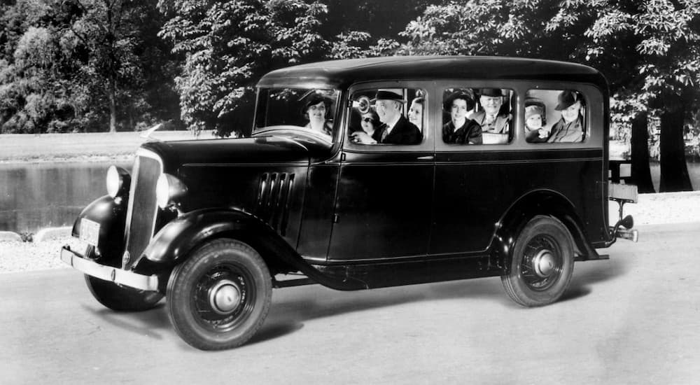 A group of people are in a 1935 Chevy Suburban Carryall in black and white.