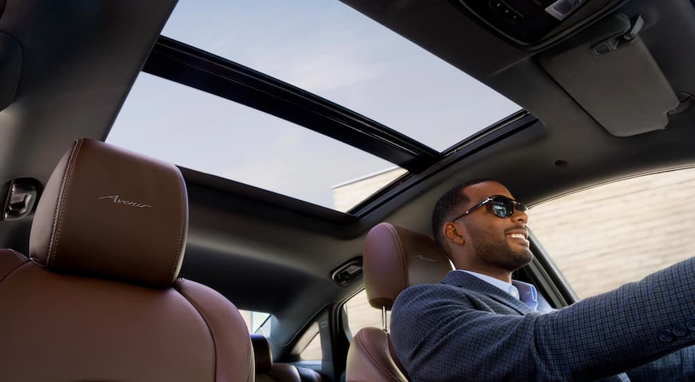 A man is happily driving his 2019 Buick LaCrosse with burgundy interior home from the Buick dealership.