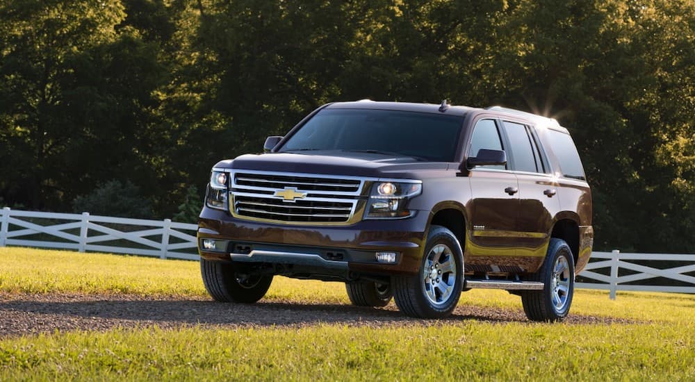 A dark colored 2016 Chevy Tahoe is on a gravel driveway through a field after leaving one of the local used car dealerships.