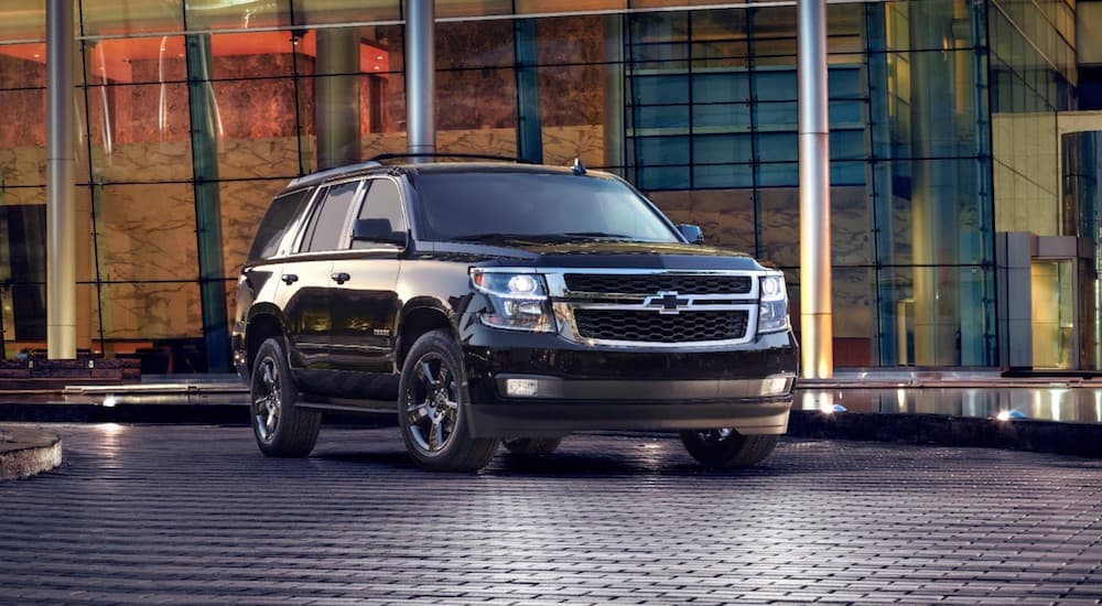 A black 2017 Chevy Tahoe is parked in front of many glass windows.