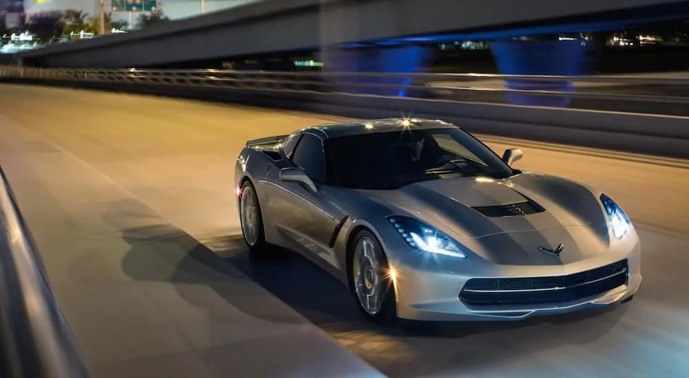 A silver 2019 Chevy Corvette is driving on a highway at night. 