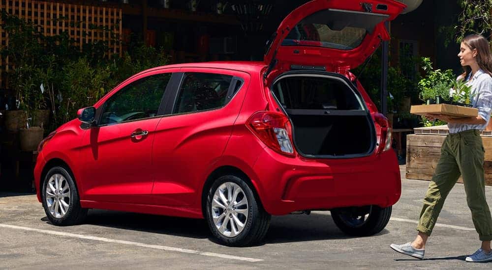 A side view of a red 2020 Chevy Spark that has the tailgate open is shown. 