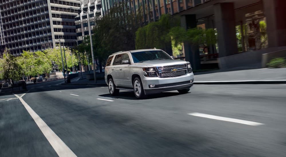 A silver 2020 Chevy Tahoe is driving on a city street.