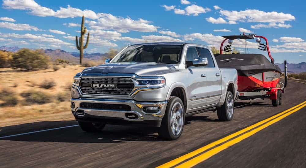 A silver 2019 Ram 1500 is towing a boat.