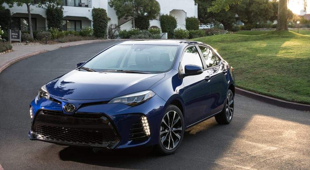 A blue 2016 Toyota Corolla, which is one of the most popular used cars on the market, is parked in front of a house. 