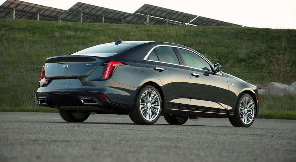A black 2020 Cadillac CT4 is parked facing a grassy hill with solar panels.