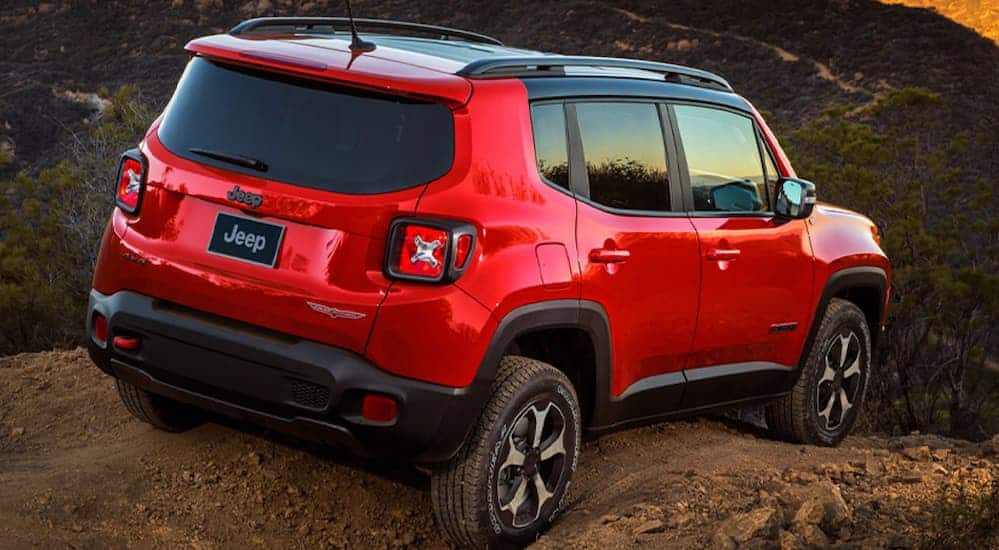 A red 2020 Jeep Renegade, which wins when comparing the 2020 Jeep Renegade vs 2020 Kia Soul, is parked on a rock over looking mountains.