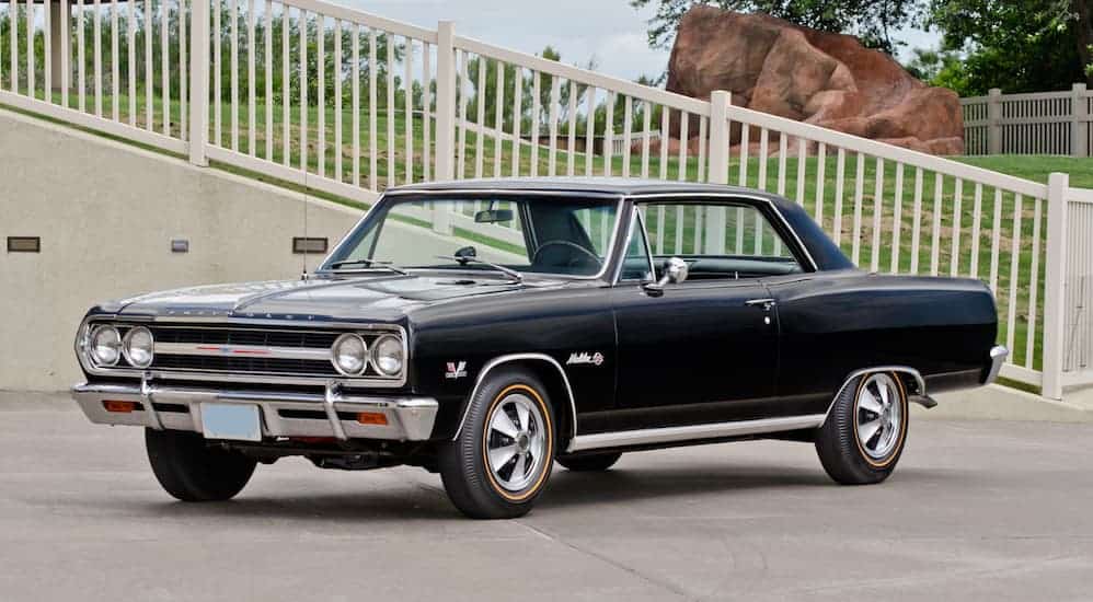 A black 1965 Chevelle SS Z16, a car you may see on display when searching for 'Chevy Dealer Near Me', is parked in a parking lot.
