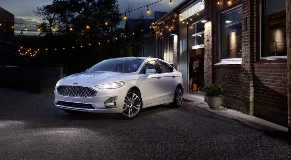 A white 2020 Ford Fusion is parked in a city at night.