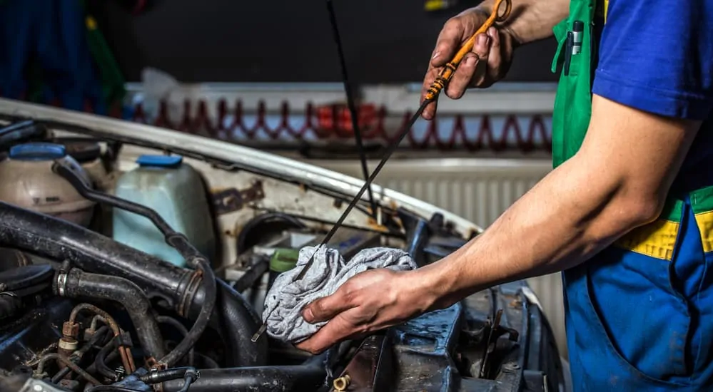 A mechanic is doing an oil change on a car in a garage. 