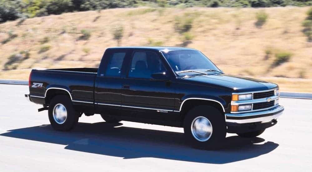 A black 1999 Chevy Silverado 1500, a great year to see The Evolution of Chevy Trucks, is driving on road in the desert. 