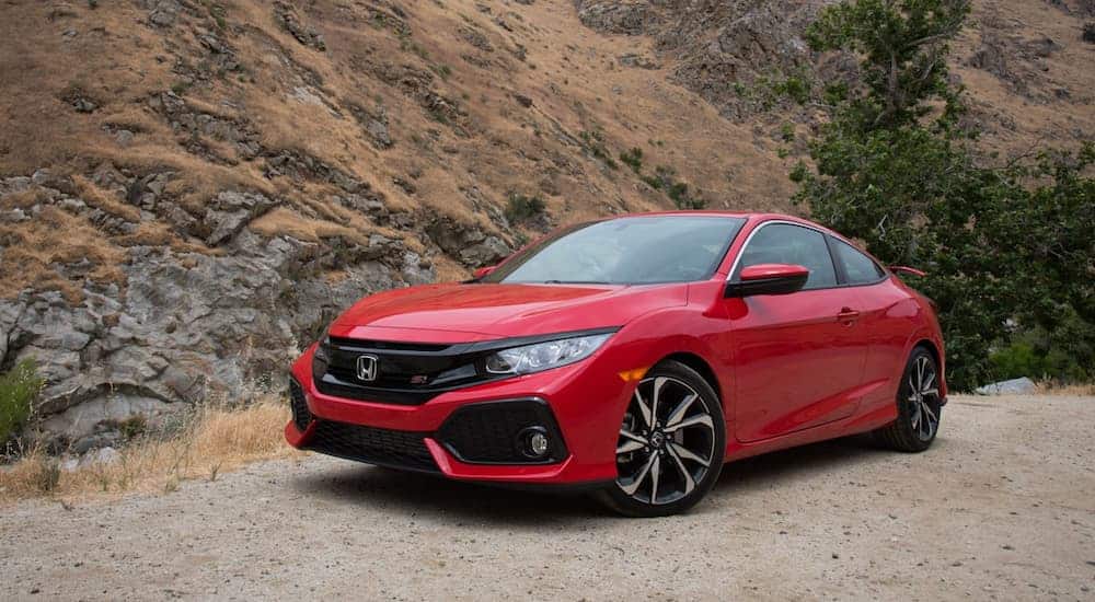 A red 2017 Honda Civic is parked on a dirt road next to a dirt hill. 