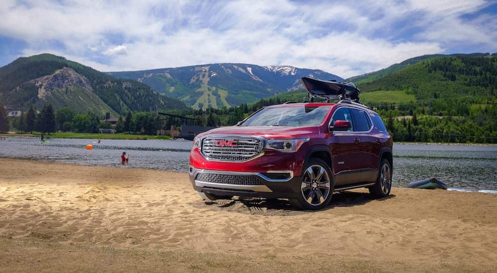 A red 2018 GMC Acadia, which is popular among used SUVs for sale, is parked next to a lake.