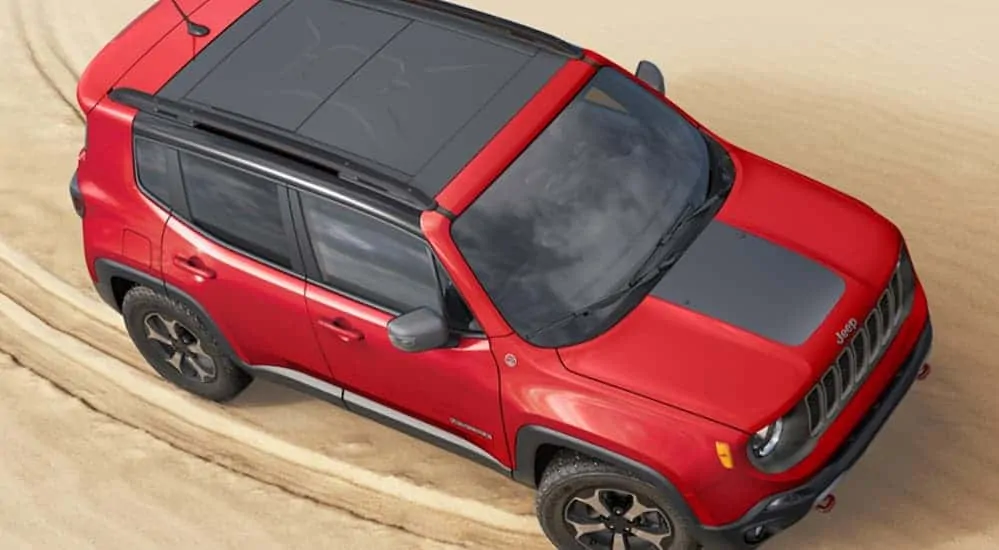 A birds eye view of a red 2020 Jeep Renegade, which wins when comparing the 2020 Jeep Renegade vs 2020 Mazda CX-30, is driving on sand.