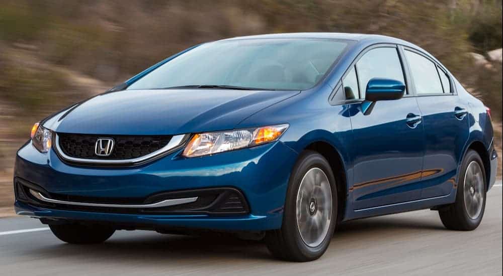 A blue 2015 Honda Civic, which is a popular used car under 15k, is driving on highway.