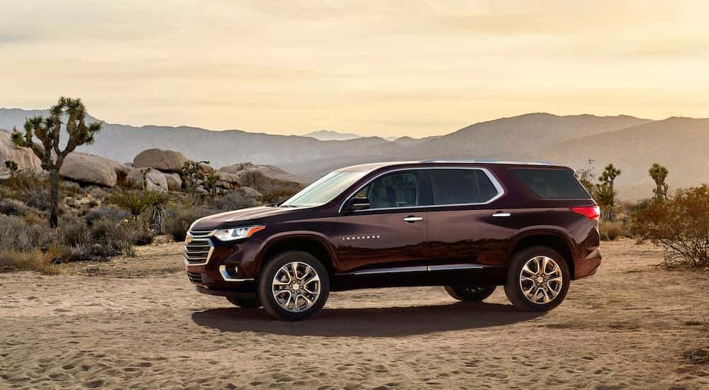 A burgundy 2018 Chevy Traverse, which is a popular option among used cars for sale, is parked on a dirt road.