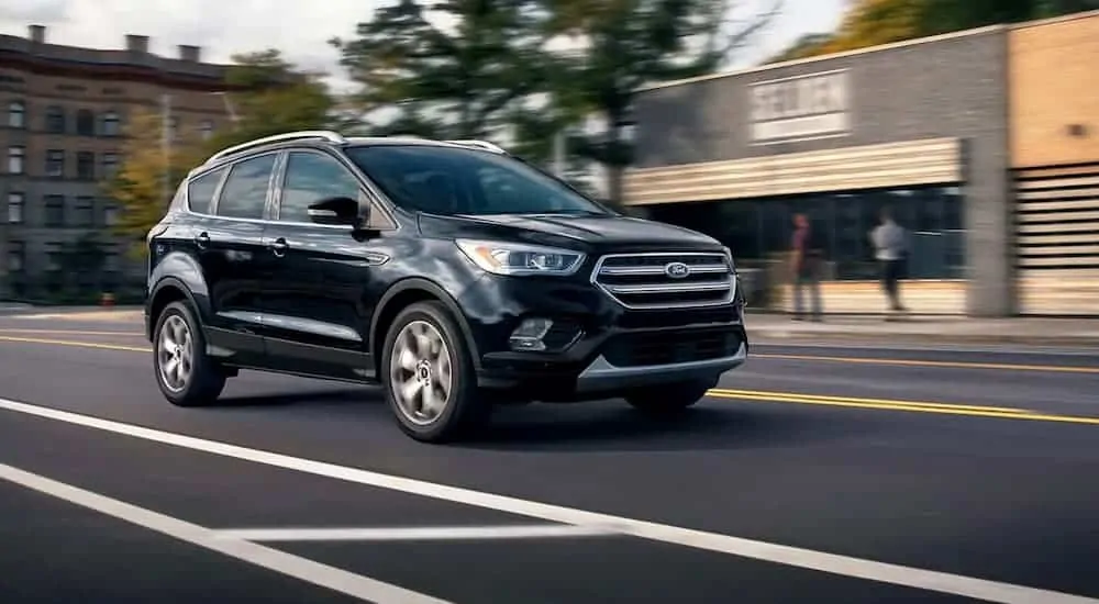A black 2019 Ford Escape is driving downtown.