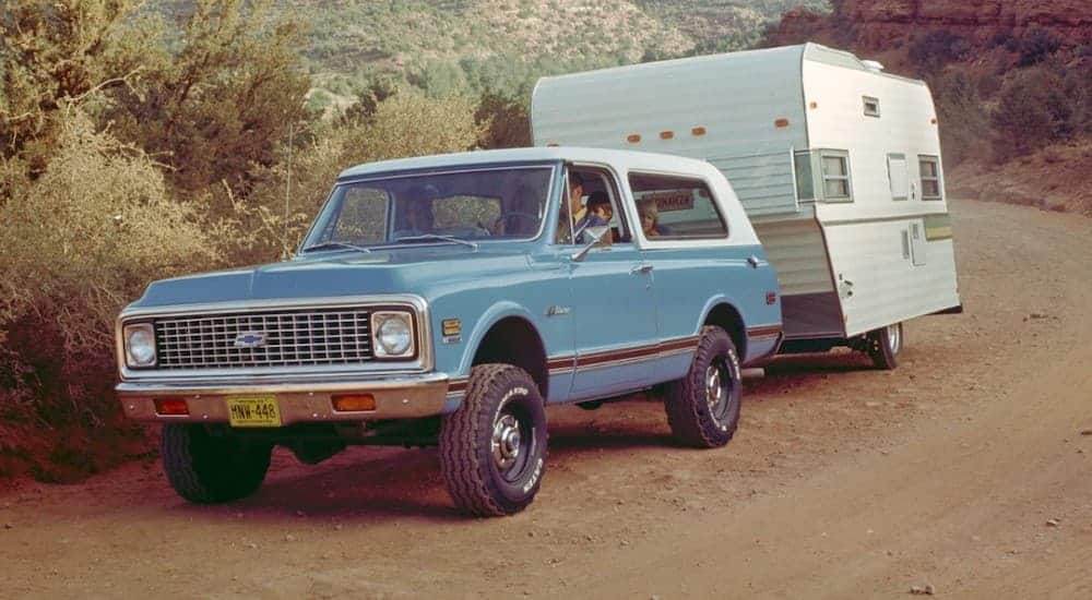 A blue 1969 Chevy K5 Blazer is towing a camper.