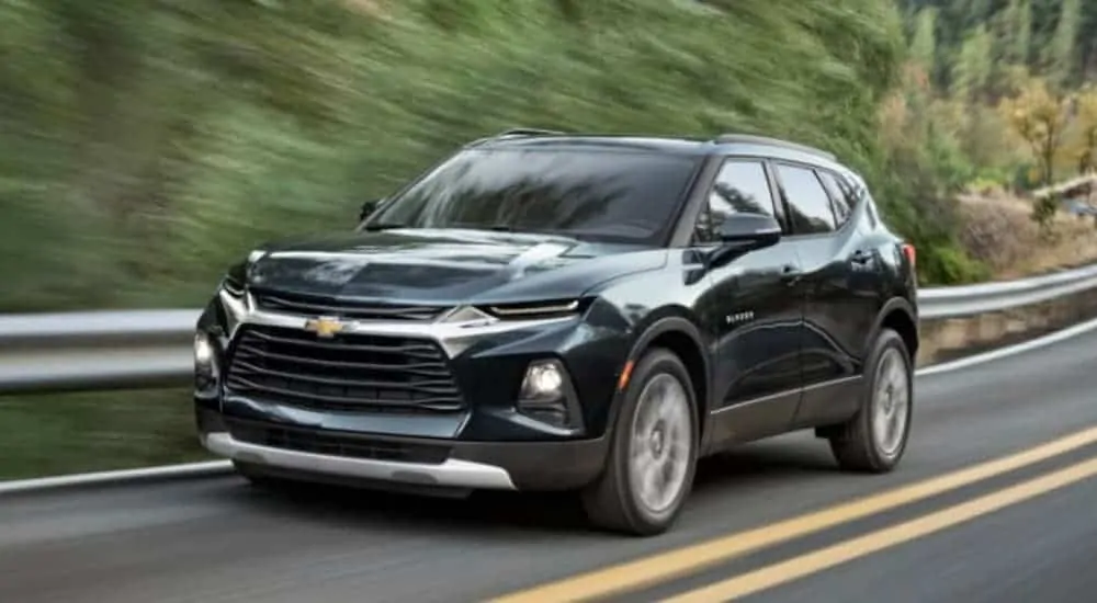 A green 2020 Chevy Blazer 3LT is driving on a treelined road.